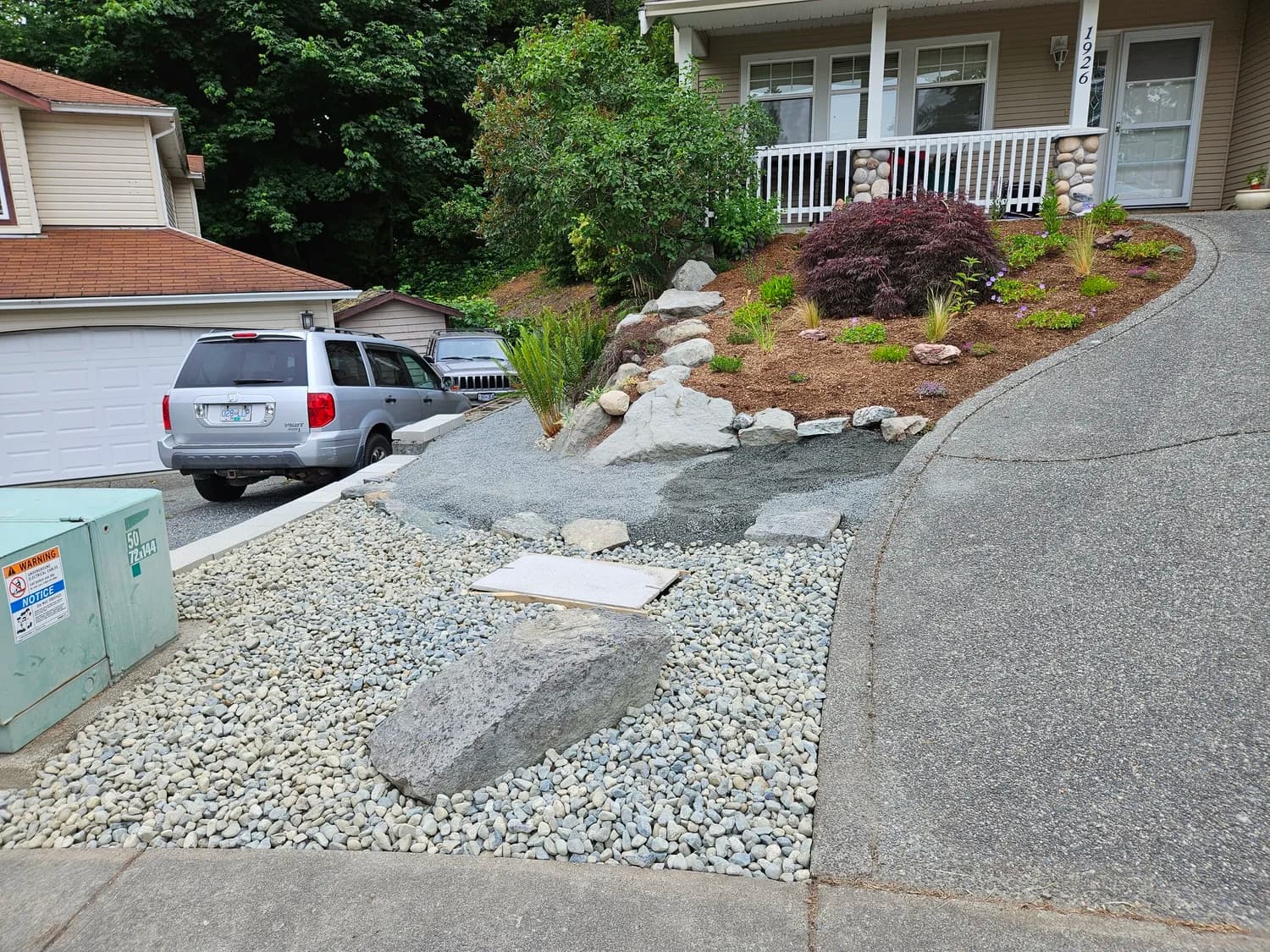 Front yard rock garden with large boulders and gravel, Japanese maple and trellis